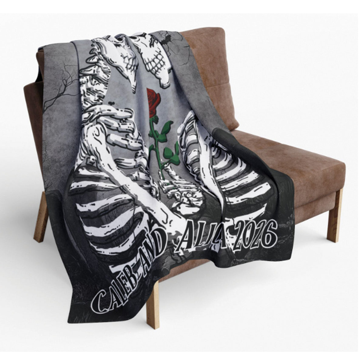 A gray throw blanket draped over a brown armchair, featuring a black-and-white skeleton ribcage design, a red rose, and the text 'CABAL AND ALA 2026' in stylized lettering.