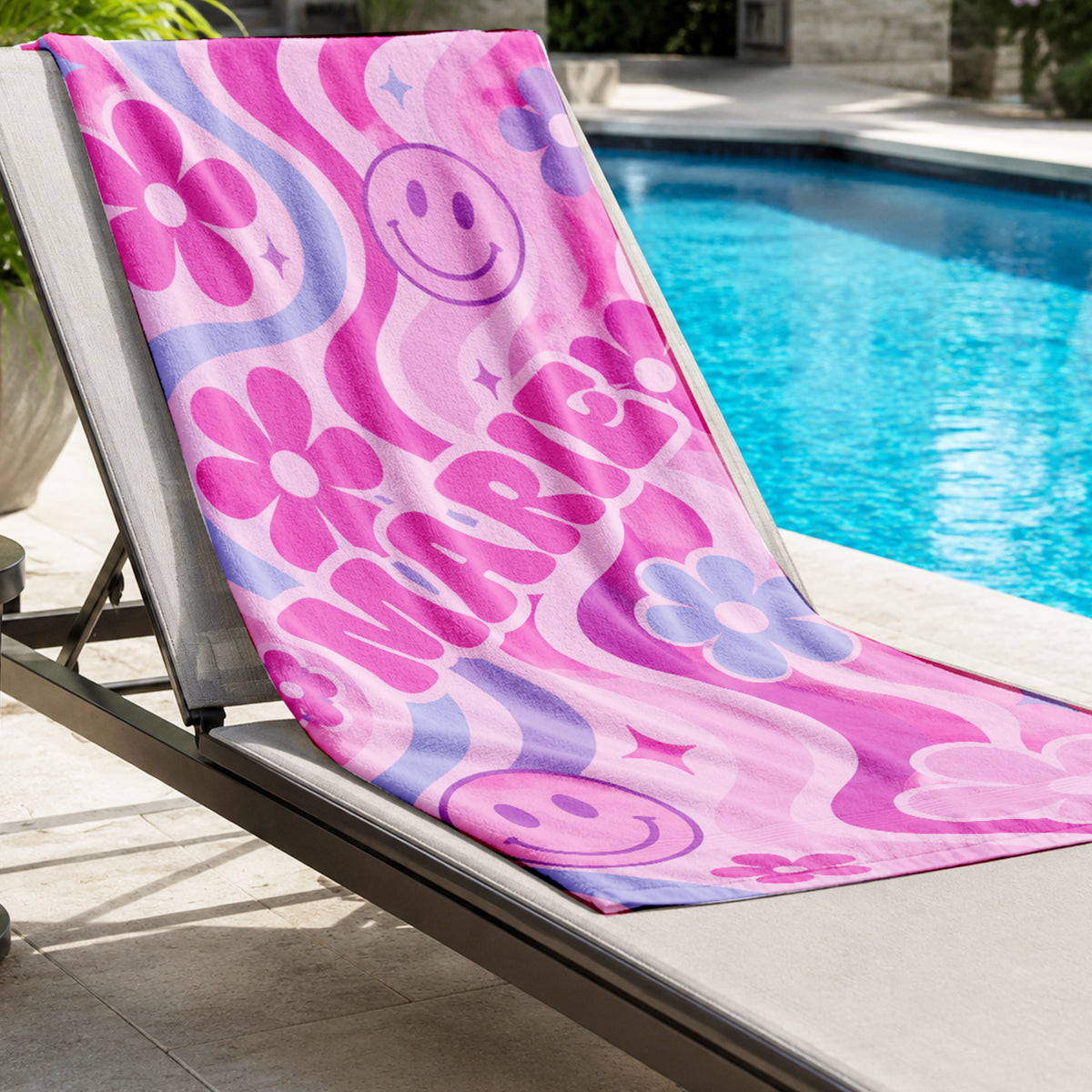 Colorful PInk beach towel with pink smily faces, pink and blue flowers on light pink background