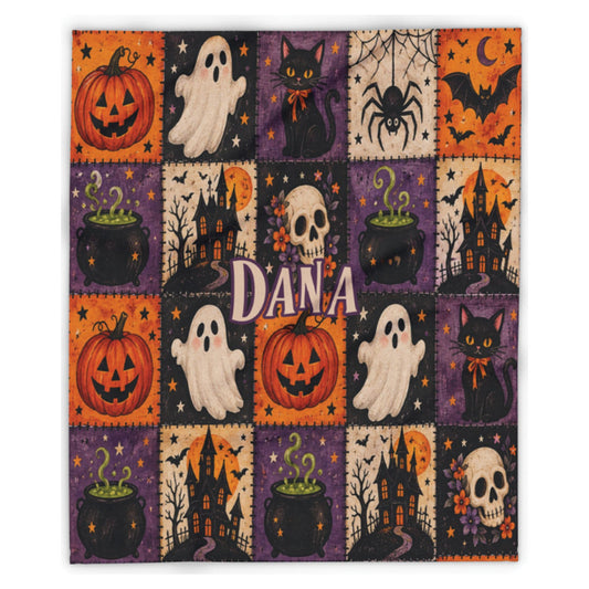 A square Halloween-themed patchwork blanket or quilt featuring a grid of orange pumpkins, white ghosts, black cats, spiders, haunted houses, cauldrons, skulls, and stars on purple, orange, and cream backgrounds. The center is personalized with the name 'DANA' in large white letters.