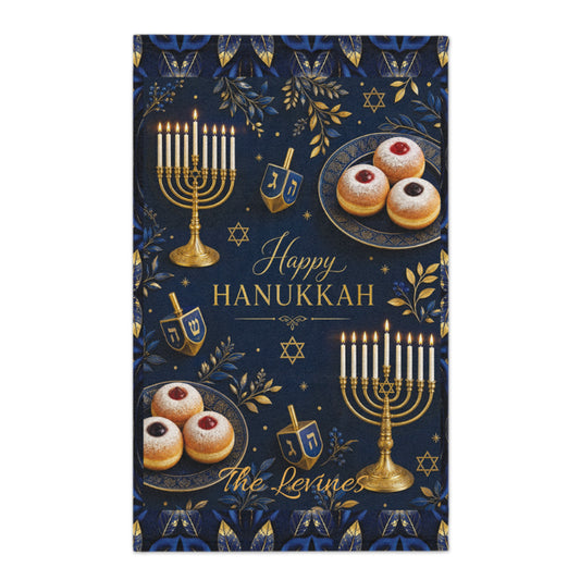 A rectangular Hanukkah decorative print or card featuring a dark navy background with gold and blue botanical motifs, gold menorahs, dreidels, star of David symbols, and pastries. The center reads “Happy Hanukkah” with “The Levines” in cursive script.