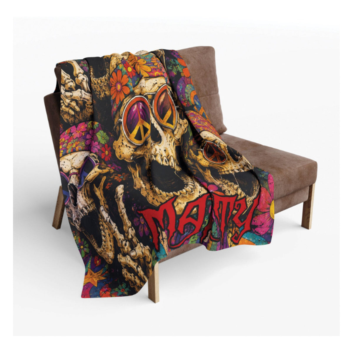 A multicolor throw blanket featuring a psychedelic design with skulls, peace signs, flowers, and the word 'Matri' in red graffiti-style lettering, draped over a brown armchair against a light gray background.