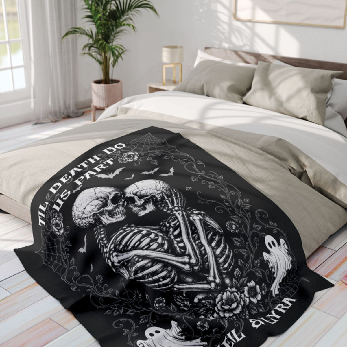 A black bedding set on a bed in a bright bedroom, featuring a large white gothic graphic of two skeletons embracing with the text 'I'LL DEATH DO HIS PART' and 'I'LL SURVIVE'.