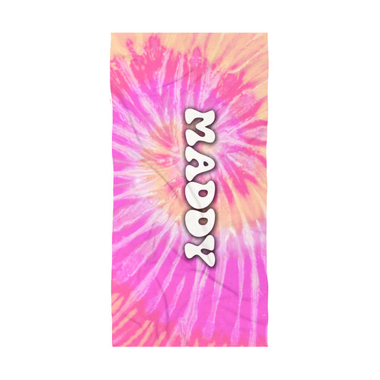 Beach towel with pale orange and pale pink tye die design with name maddy in a bubbly retro font in water