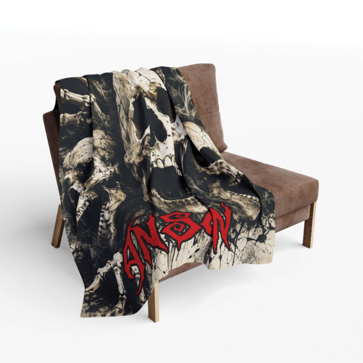 A black and off-white skull-patterned throw blanket with a bold red 'Sanson' logo, draped over a brown armchair against a light gray background.