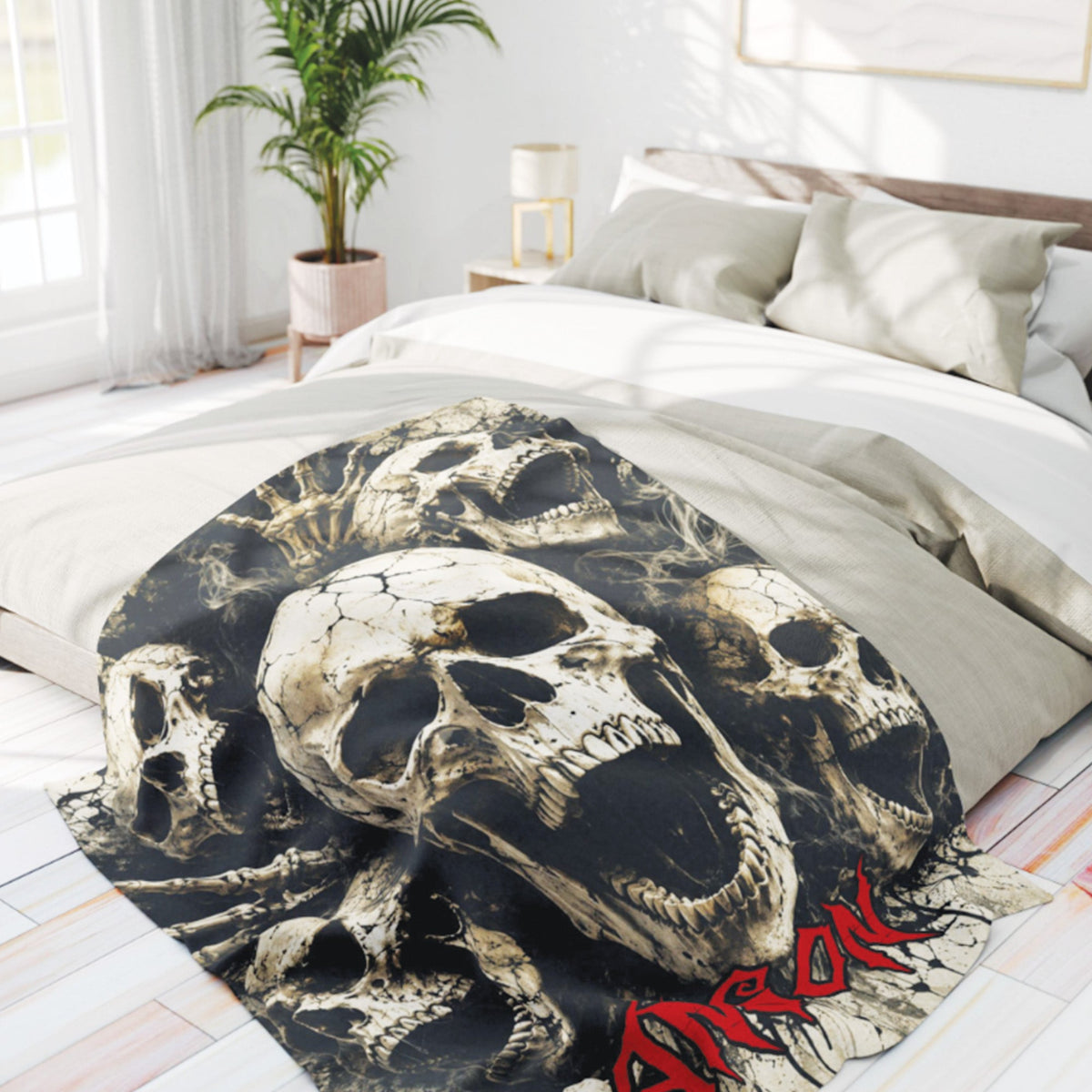 A black throw blanket featuring a detailed skull print and the word 'GORILLKA' in red, draped over a bed in a bright, modern bedroom.
