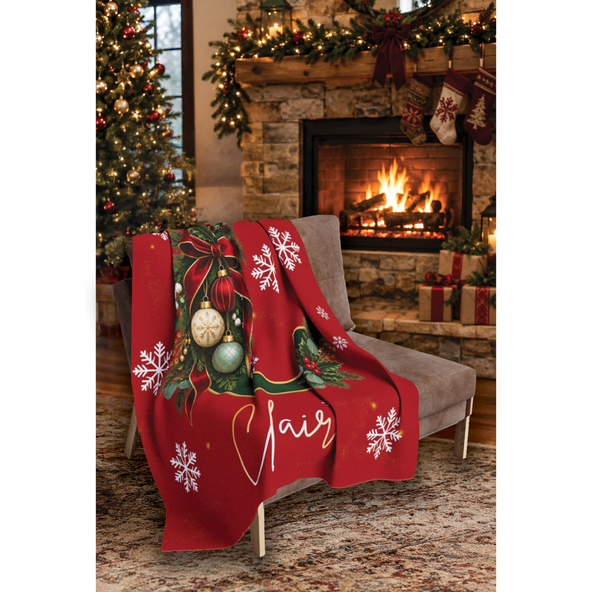 A red Christmas-themed throw blanket draped over a gray armchair in a cozy living room setting with a fireplace, stockings, and a decorated tree.